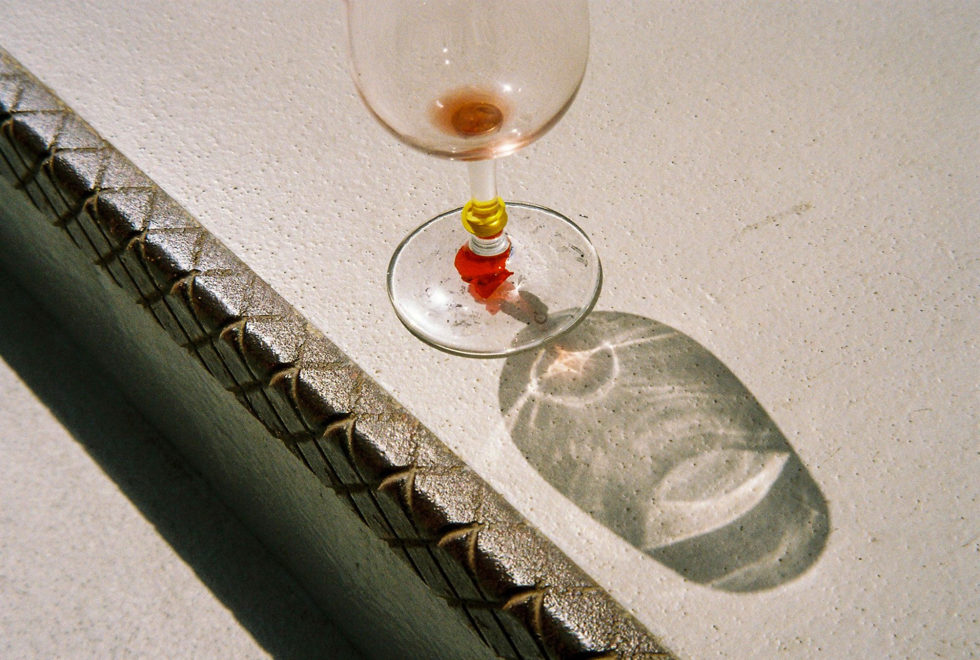 A wine glass on a white ledge, its shadow beside it