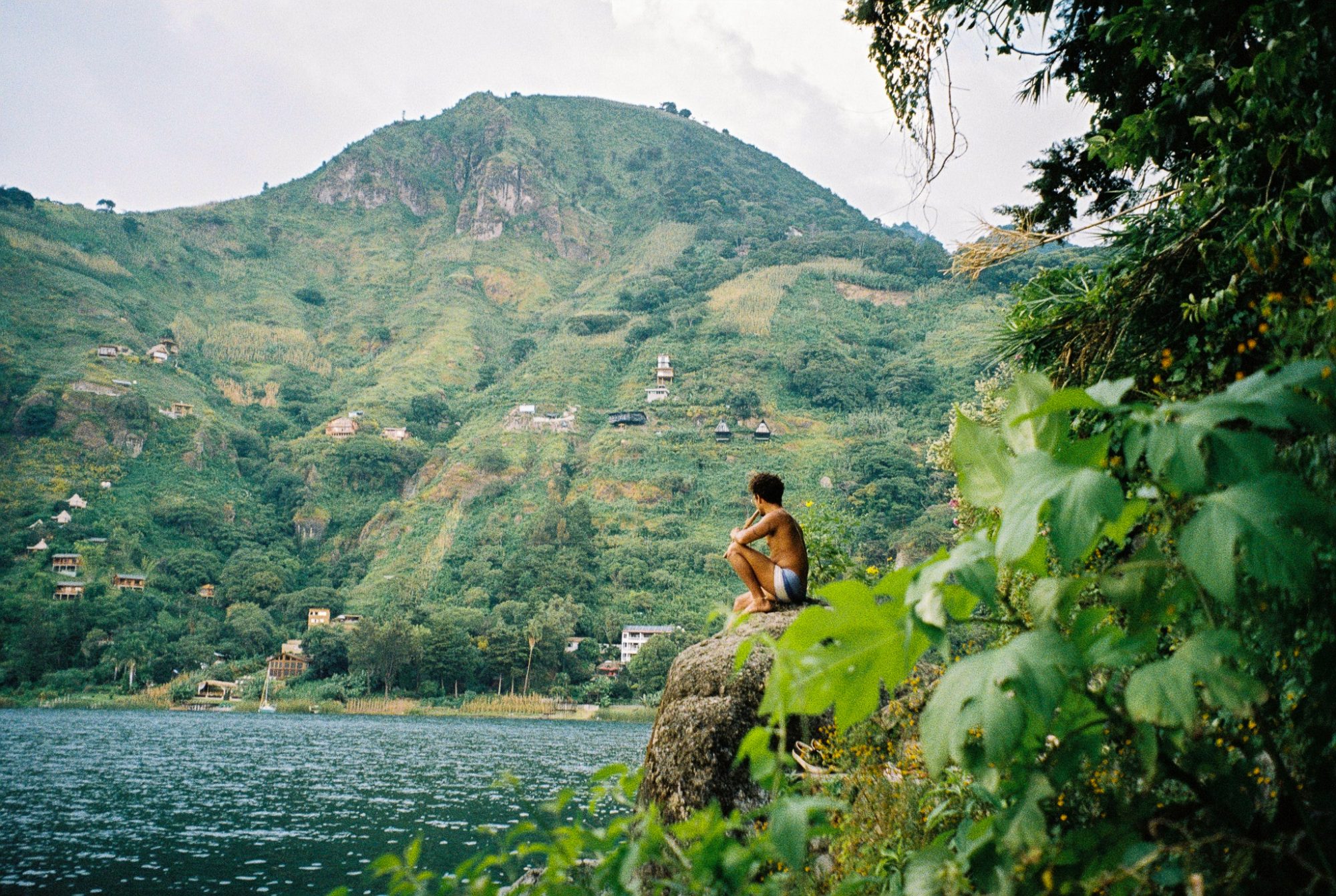 A boy sitting on a rock above the lake