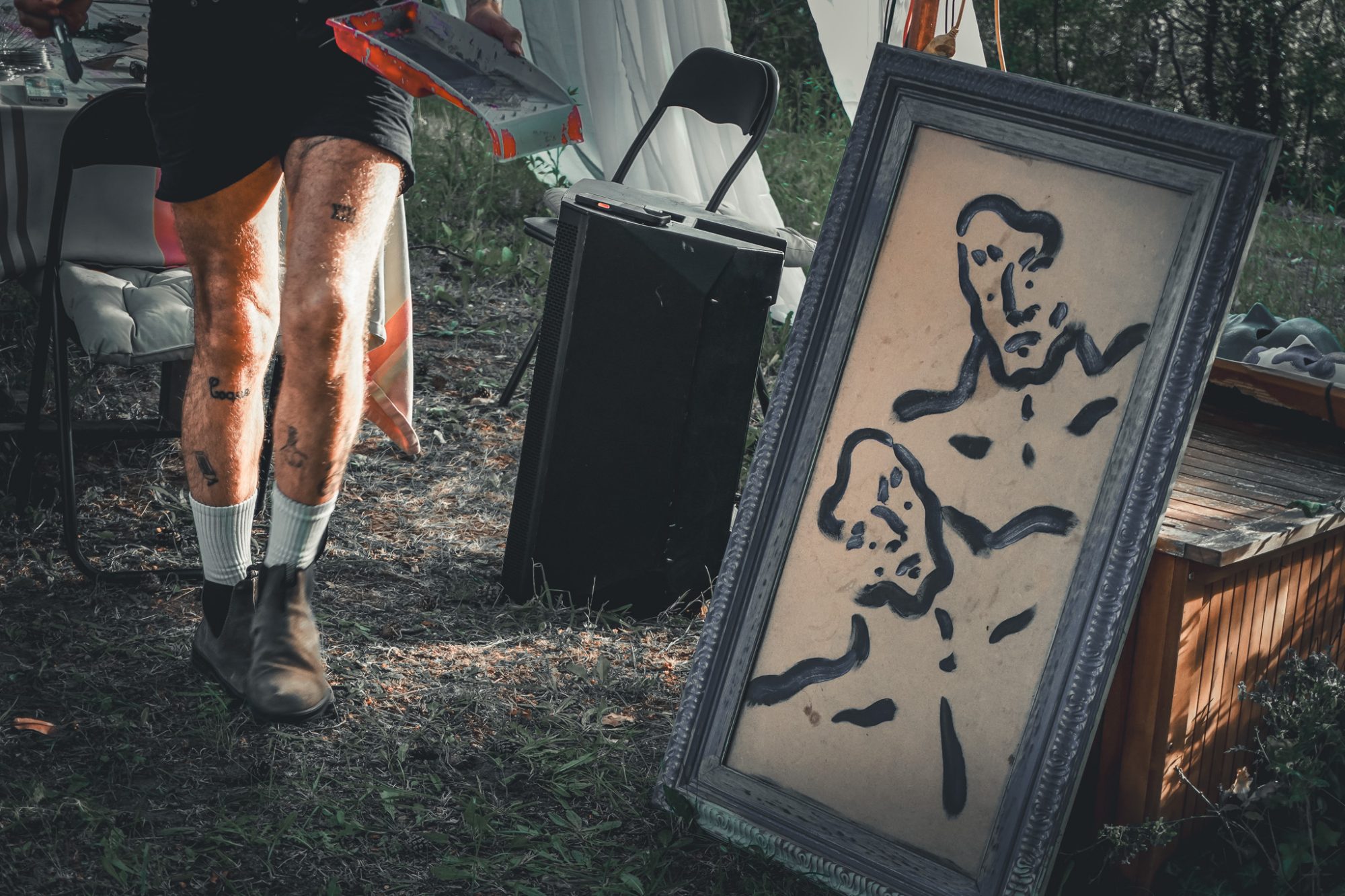 Legs walking past a framed painting of two faces