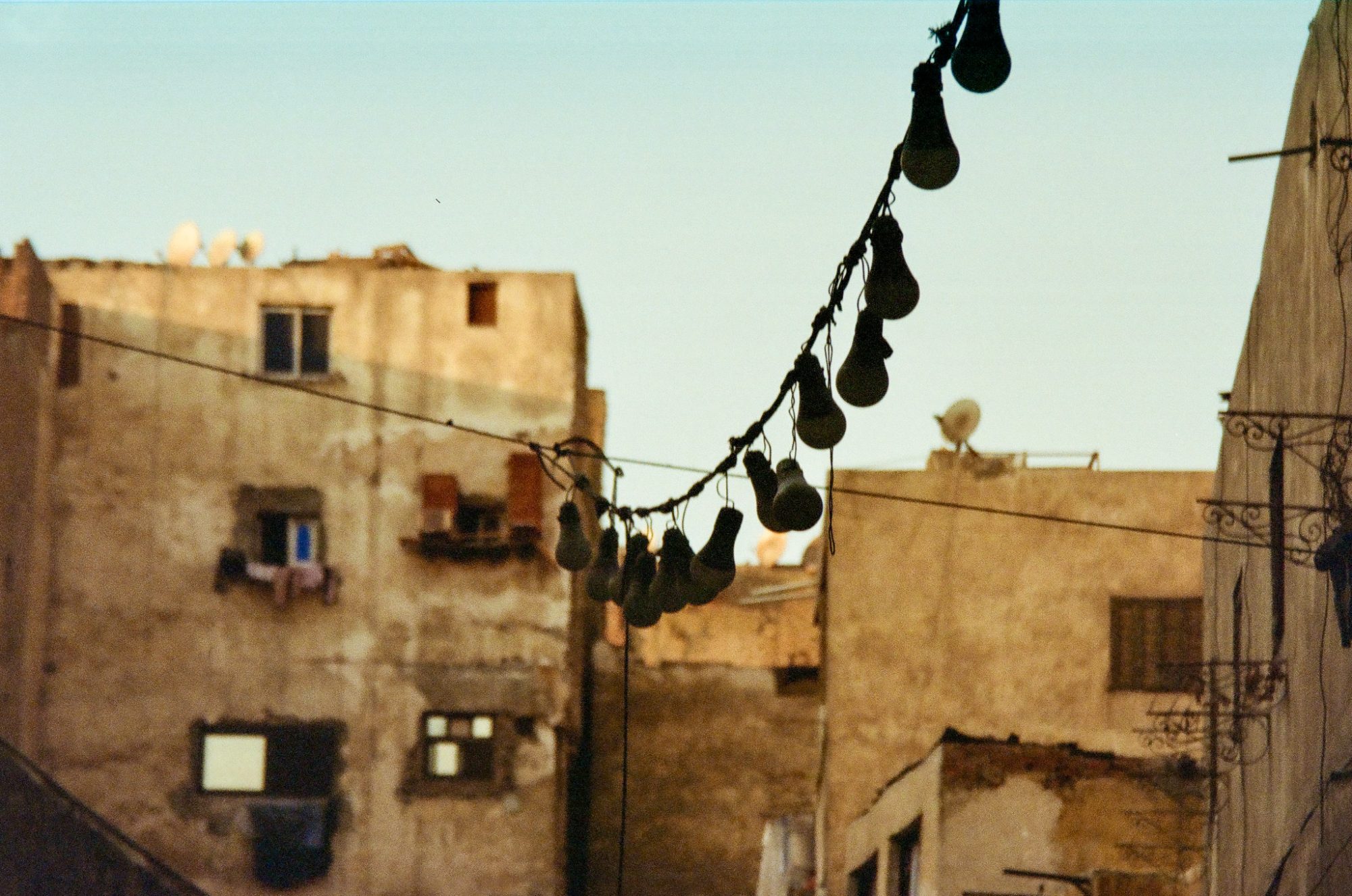 Bulbs strung on a wire above the rooftops