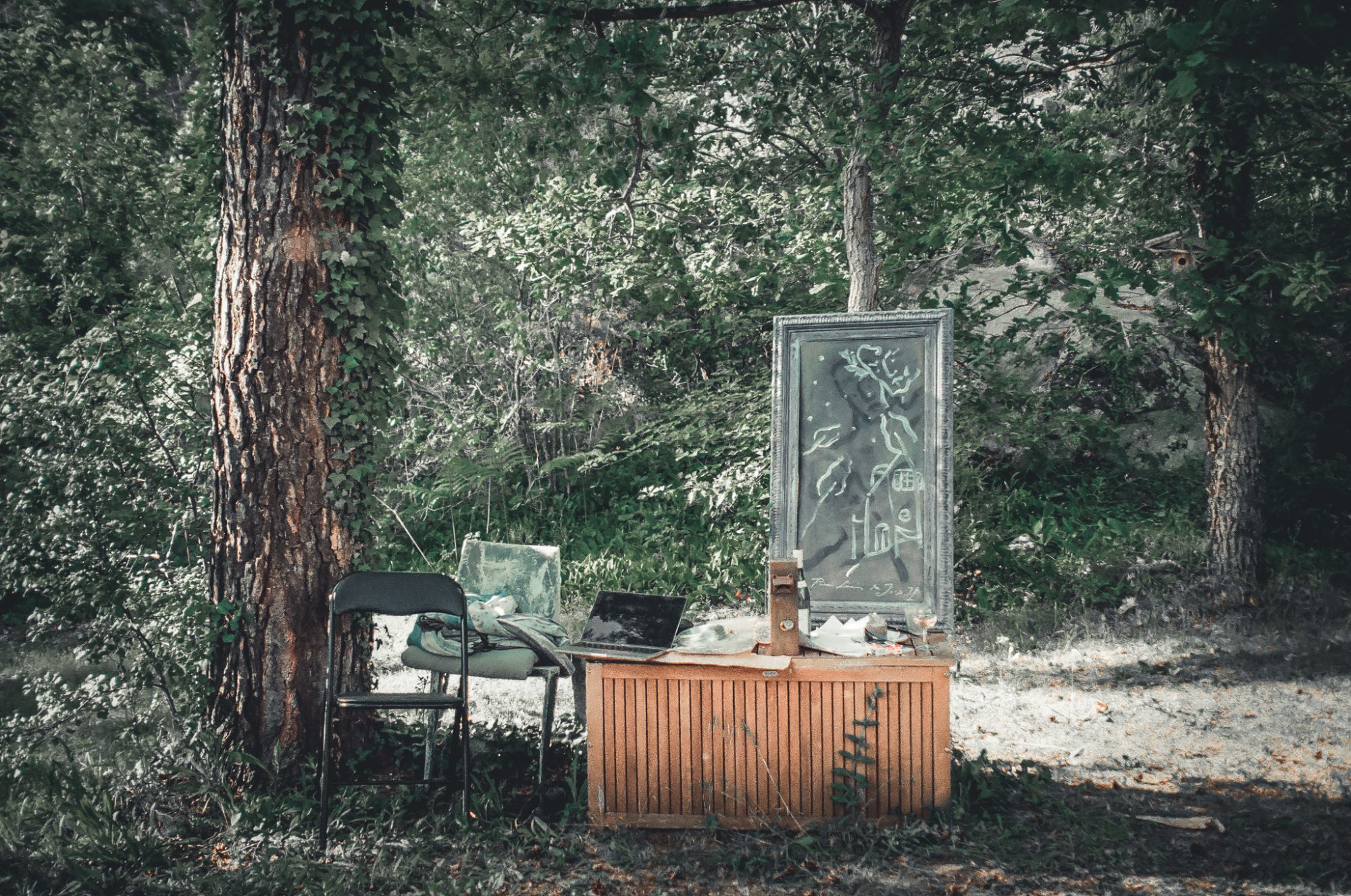 A framed painting propped against a table in the forest